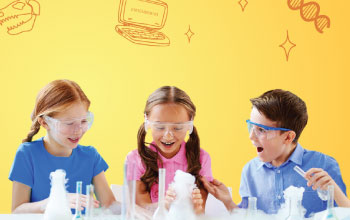 2 girls and a boy laughing and playing with test tubes.  smoke coming out of 3 beakers